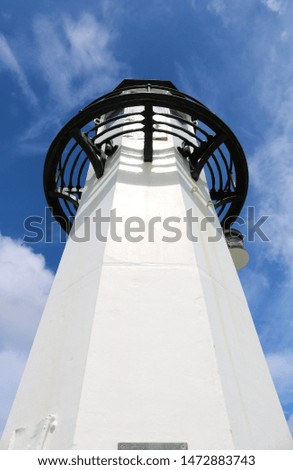 A view of a harbour lighthouse against a deep blue sky.