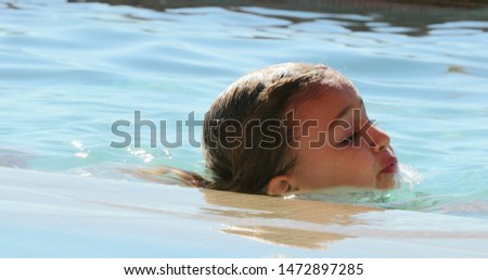 Little girl swimming at the pool during summer vacations.