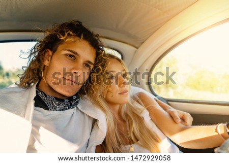 Young couple portrait inside vintage car with flare. Romantic lifestyle real image.