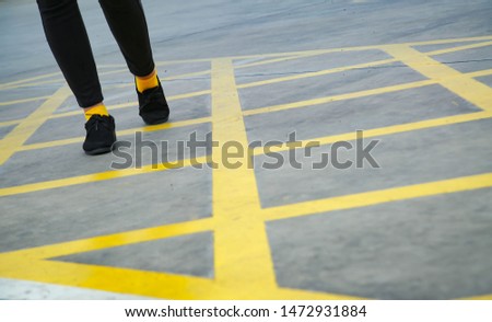 The girl wearing black trousers  Yellow sock And black shoes Walk in the parking area With lifestyle and vintage background images.