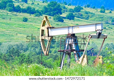 Oil and gas industry. Work of oil pump jack on a oil field. White clouds and blue sky 