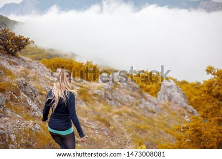 rear view young sport woman travels through the sky above the sky. girl like hiking adventure/ wearing sports clothes