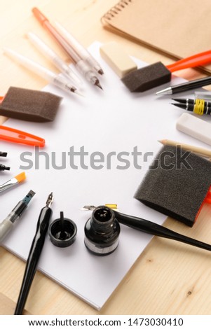 Calligraphy concept, accessories and tools for beautiful handwriting,pencils,pens,  ink, brush, eraser, pencil case,sponge, writing training,blank sheets of white paper and cardboard craftin