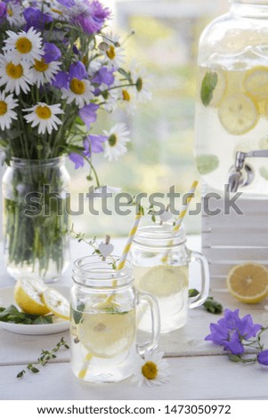 Handmade citrus limonade in jug with sliced lemon and mint decorate thyme and with flowers at the village