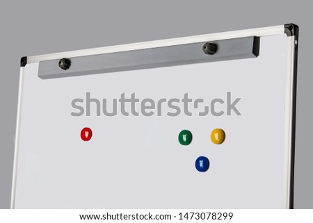 White magnetic whiteboard for markers on a gray background with four colored magnets: red, green, blue, yellow. The concept of study and planning.