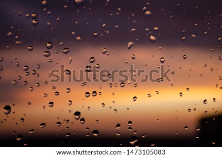 Drops of water on the glass. Sunset. Orange, purple and golden sky