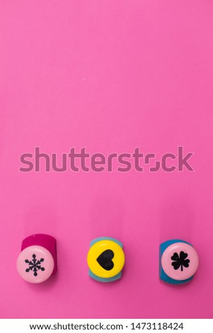 three curly staplers on a pink background