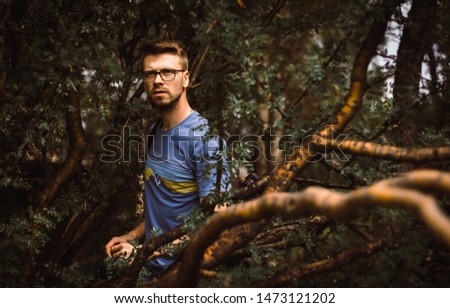 Portrait of male photographer hiking with his camera gear taking pictures in the trees trying to find the perfect shot in the forest 