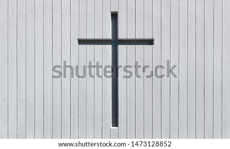 Cross in a white wall made of exposed concrete with vertical stripe pattern