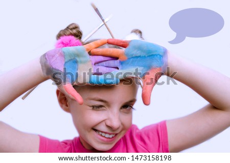 Child with cross painted palm hand winking. Have fun in art school class.Cute little kid with paint brush in hair. Isolated portrait with empty cloud sign for text.