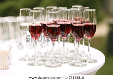 lots of glass goblets with red wine at a party, great red wine outdoors.