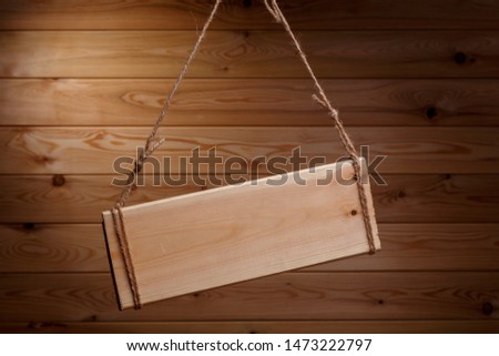 Wooden signboard on a rough rope on a beautiful wooden background