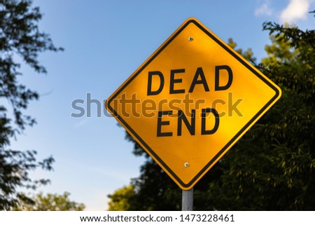 Vibrant yellow Dead end sign against the bright blue sky and green summer trees in Madison, Wisconsin.