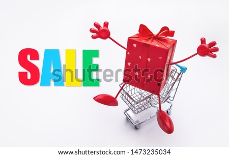 Festive red box with legs and hands in  shopping cart. Discounts, sale.