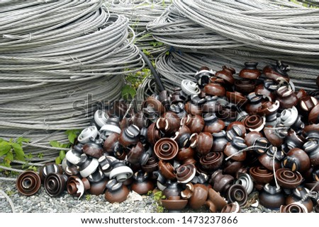 Photo of rolls of metal or steel cables and insulators used for electric poles at an industrial yard