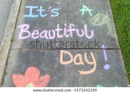 the words "It's a Beautiful Day" written with sidewalk chalk on gray concrete pavement background