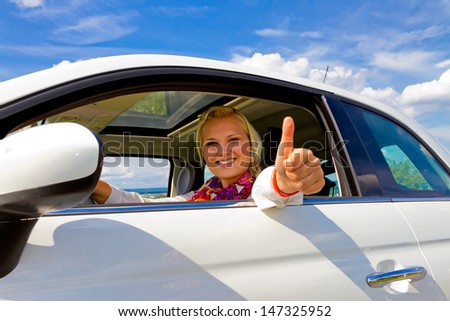 Young woman in her new car, with thumb up