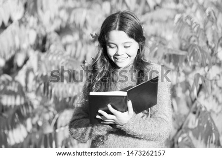 There is no end to education. Small child read book on autumn day. Small child enjoy reading on autumn landscape. Even little children looking at a picture book are using their imagination.