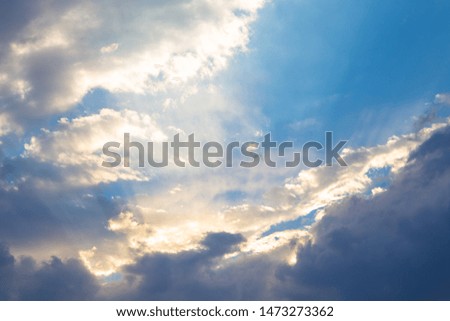 blue sky with clouds backlit by the soft rays of the sun.