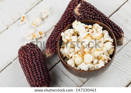 Fresh popcorn in bowl on white wooden table. Selective focus.