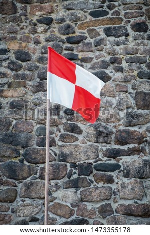 Red and white flag on a background of an ancient fortress wall