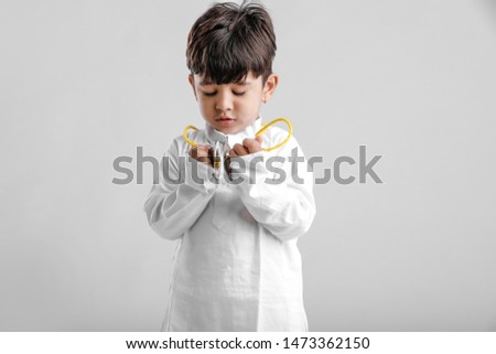 Indian Little Boy in Traditional Dress and learning with Musical instrument 