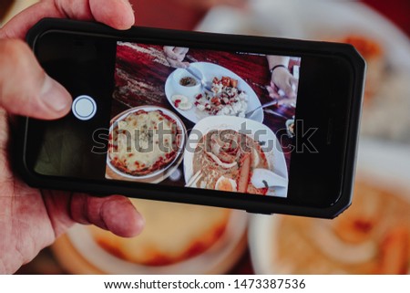 Woman taking photo on cellphone on thai food from top view