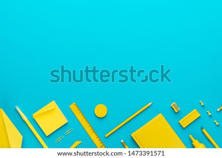 Top view photo of yellow stationery over turquoise blue background with copy space. Flat lay image of different stationary objects as back to school concept.