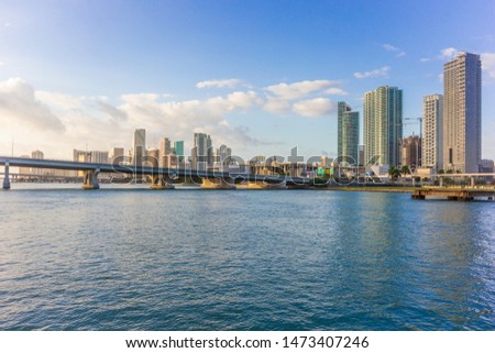 Miami city skyline panorama at blue sky cloudy with urban skyscrapers and bridge over sea with reflection