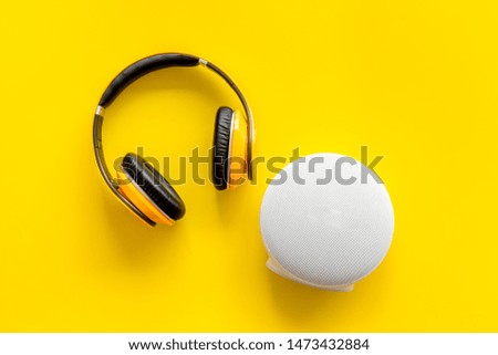Portable wireless speakers and headphones as gadgets for listen to the music on yellow background top view