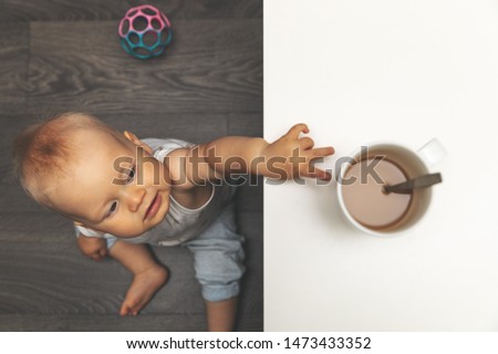 child burn and scald injury concept - little boy reaching for hot drink mug on the table Royalty-Free Stock Photo #1473433352