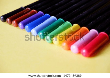 Multi-colored pens arranged in row, top view.