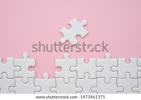 The last piece of jigsaw puzzle to complete task on pink background. Business strategy teamwork, problem solving concept. Teamwork is collaborative effort of team to achieve goal or complete mission.