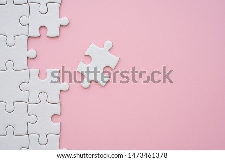 The last piece of jigsaw puzzle to complete task on pink background. Business strategy teamwork, problem solving concept. Teamwork is collaborative effort of team to achieve goal or complete mission.