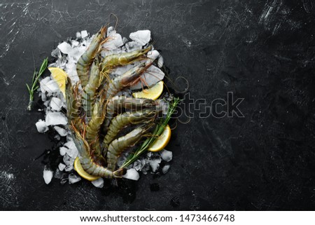 black tiger prawns with lemon on ice. Seafood. Top view. On a black background. Free copy space. Royalty-Free Stock Photo #1473466748