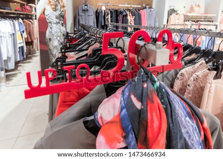 Sale sign with a discount 50% in the women's clothing store. Colorful dresses on hangers in a retail shop. Season sale, fashion and shopping concept