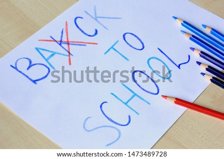 Back to school concept. Seven colored pencils on a white sheet of paper with words 'back to school' with specially made mistake. Selective focus.