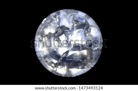 transparent glass cracked ball through which light shines on a black background