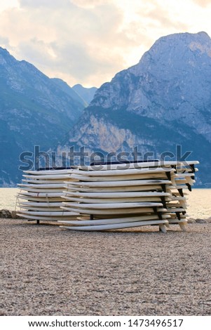 Windsurfing boards storage on a beach watersports facility. Stocked boards at sunset on the lake Garda