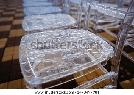 Transparent plastic chairs with rain drops on the surface. Bad weather spoiled the ceremony in the open air. 