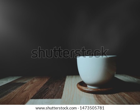 White cup of coffee and vapor on dark background with left side lighting effect. Vintage tone color