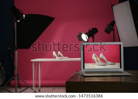 Shooting of women's shoes for product promotion in photo studio, focus on laptop