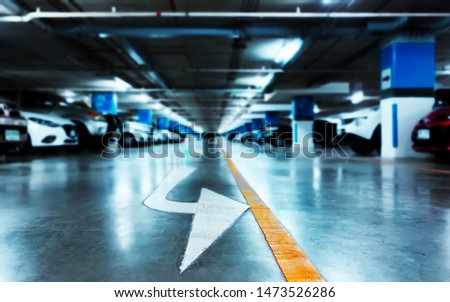 Blurred background of indoor parking lot at night with an exit arrow and yellow straight line on the floor