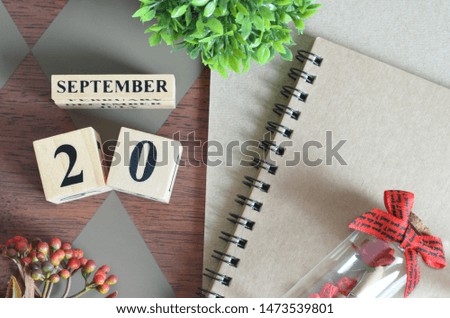 September 20. Date of September month. Number Cube with a flower, Rose bottle and notebook on Diamond wood table for the background.
