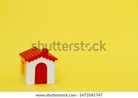 Little toy house on a yellow background.
