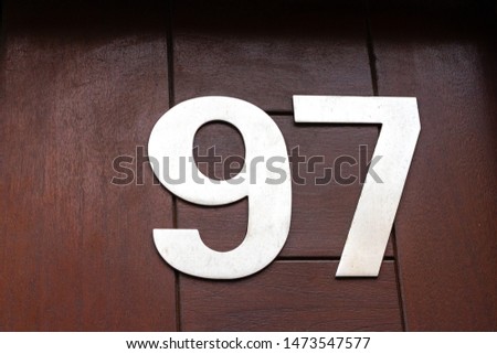 House number 97 in large silver digits on a brown wooden front door