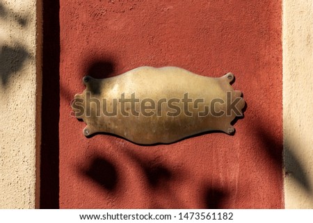 Closeup of an old empty brass plaque with copy space on a red and white wall. Photography