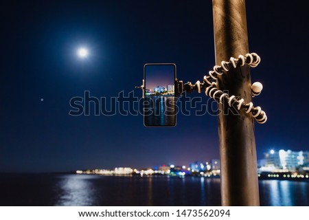 Using smartphone on flexible tripod to making the photo of sea night landscape