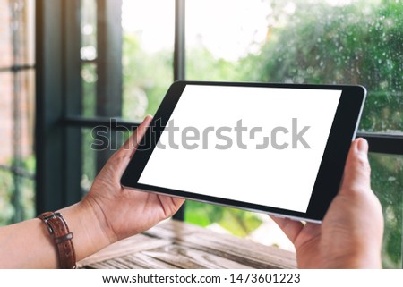 Mockup image of a woman holding black tablet pc with blank white desktop screen 
