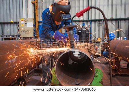 Male worker grinding use electric wheel grinding pipe sparks inside industrial construction.